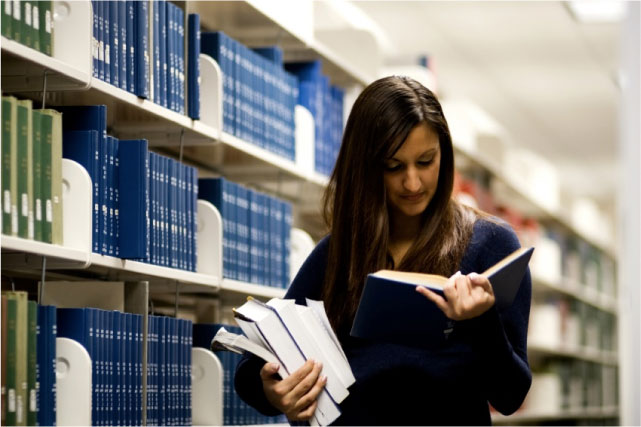 Girl Reading a Book in the Stacks