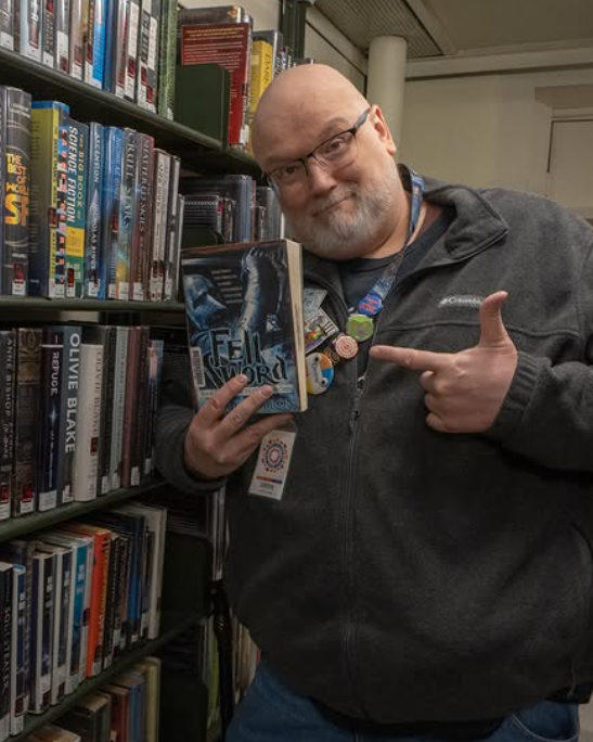 A Seymour Library staff member poses with a book for Library Shelfie Day