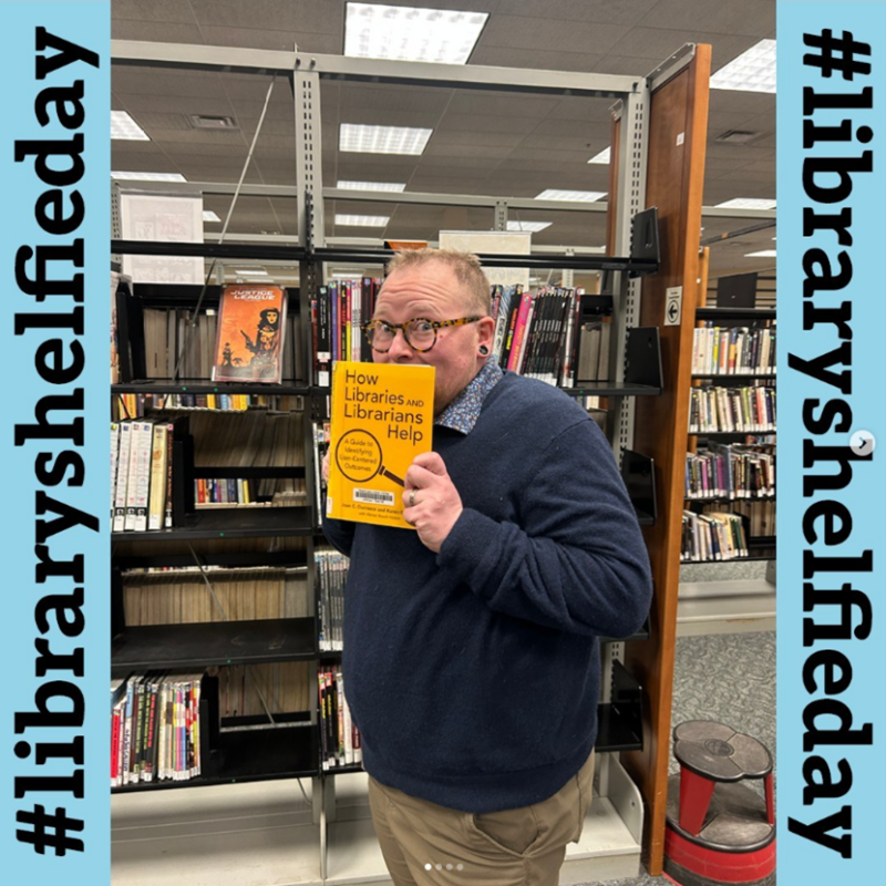 TCPL director Emerson poses with a yellow book for Library Shelfie Day