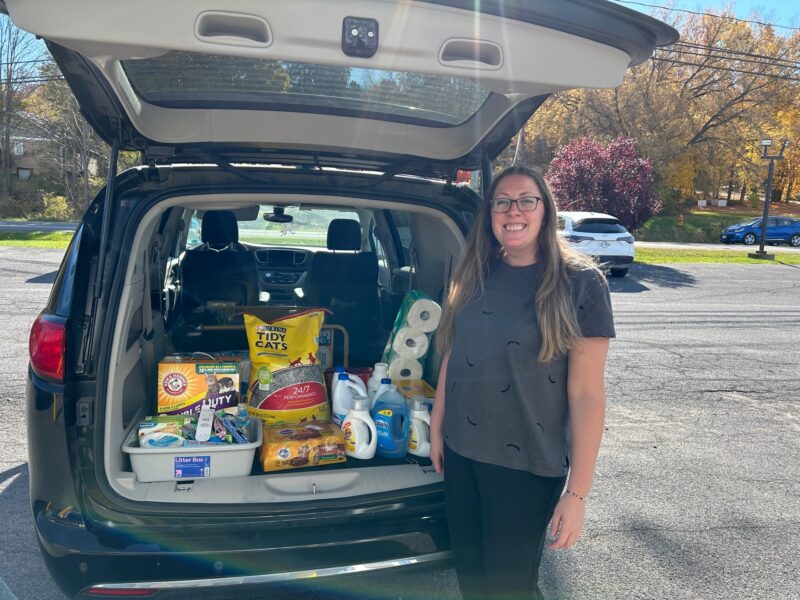 woman standing next to a van full of donations for the spca