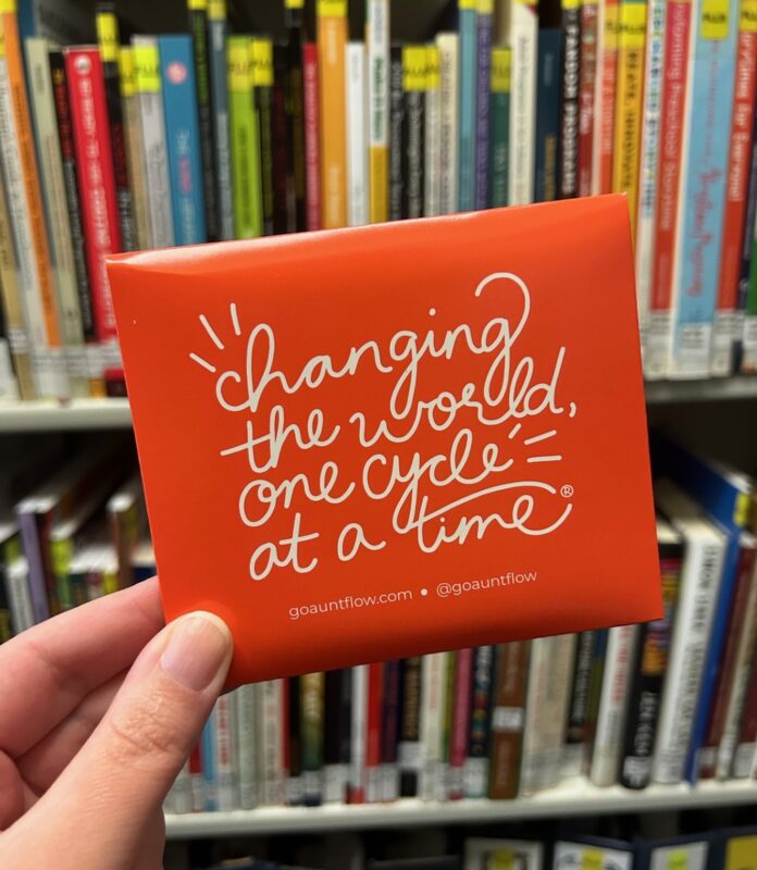 hand holding a period pad that says "changing the world one cycle at a time"