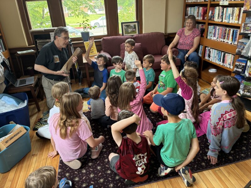 A shows fossils to a group of children at the library