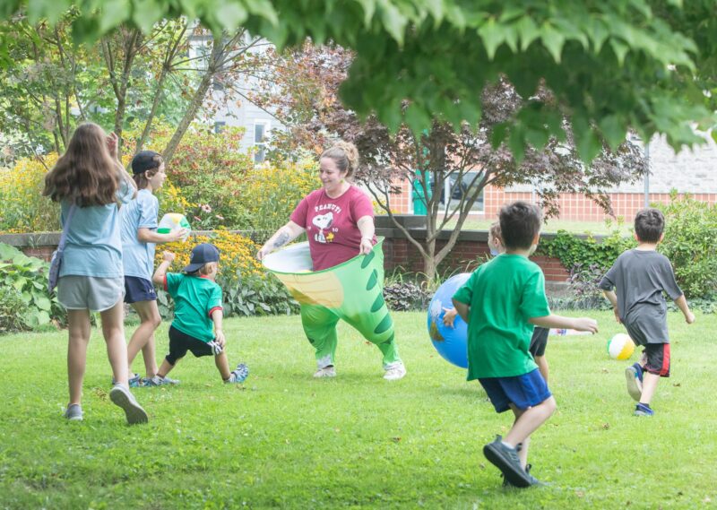 Miss Jill wears huge dinosaur pants and plays with library kids