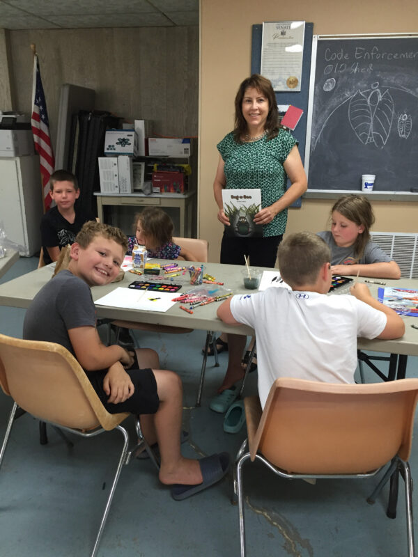 a teacher helping students create art