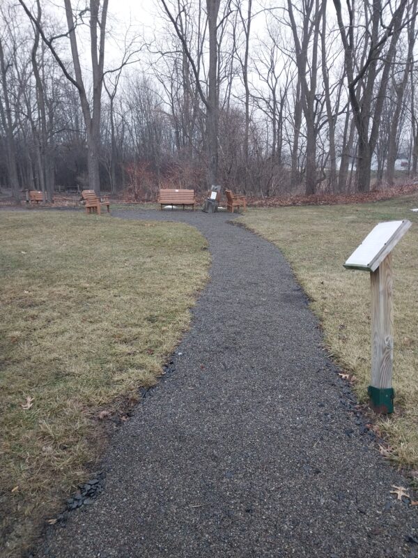 a gravel trail in the woods with benches