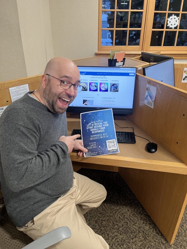 a man smiles showing a poster for tech time